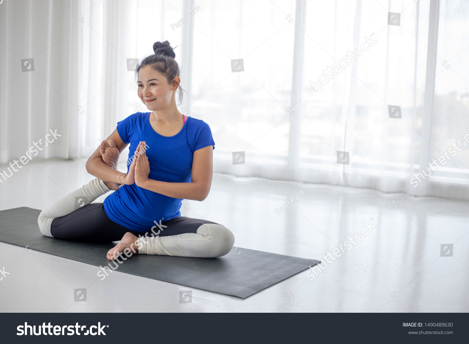 portrait beautiful young asian woman sitting on black mat in yog
