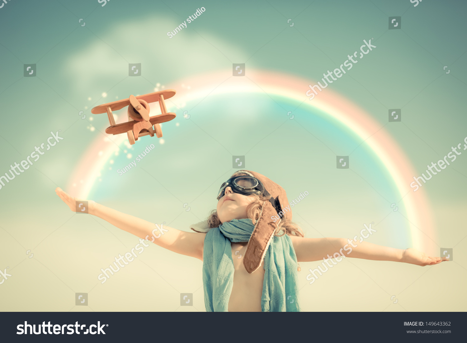 Happy kid playing with toy airplane against summer sky background