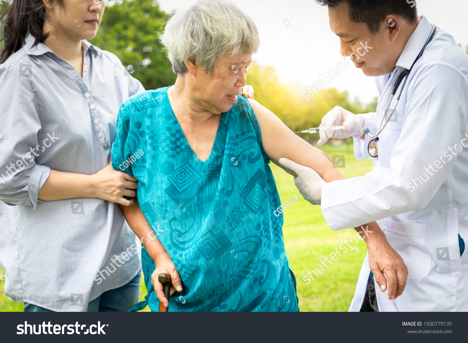 Male asian doctor with syringe doing injection vaccine flu influenza in the shoulder of senior woman family doctor injecting vaccinating elder patient in park vaccination medicine health care concept