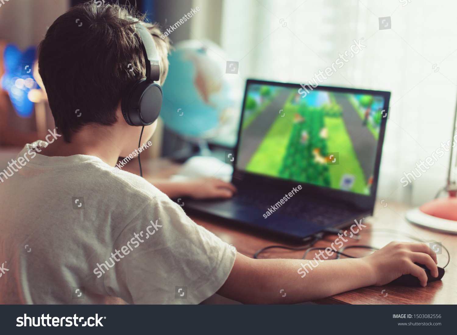 Little dependent gamer boy playing on laptop at home