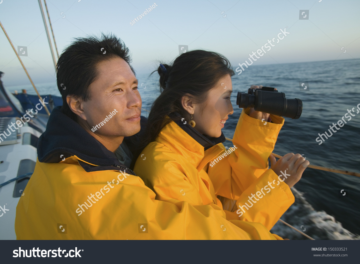 Side view of woman looking through binocular with man on yacht