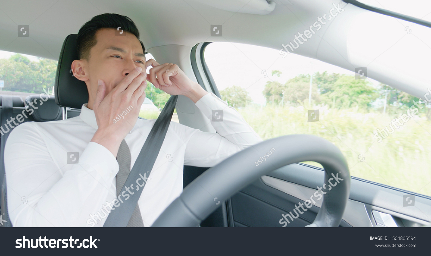 business asian man yawn in an autonomous self driving car