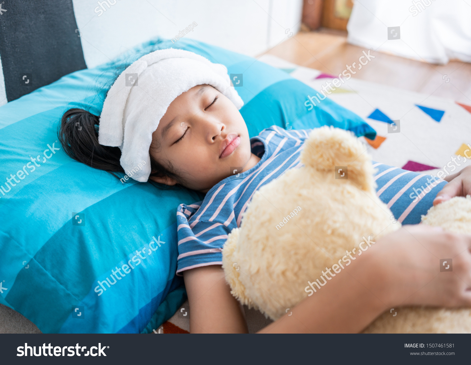 Sick little girl sleeping in bed room at home Compress on forehead.