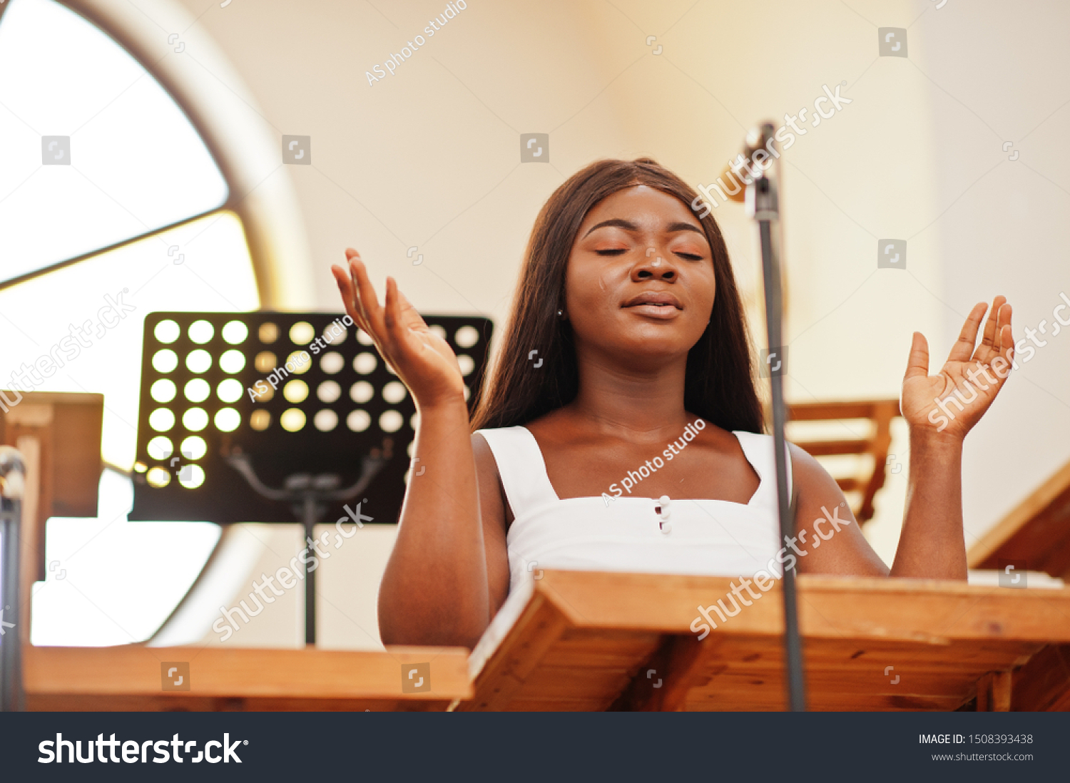 African american woman praying in the church. Believers meditates in the cathedral and spiritual time of prayer. Afro girl singing and glorifying God on choruses.