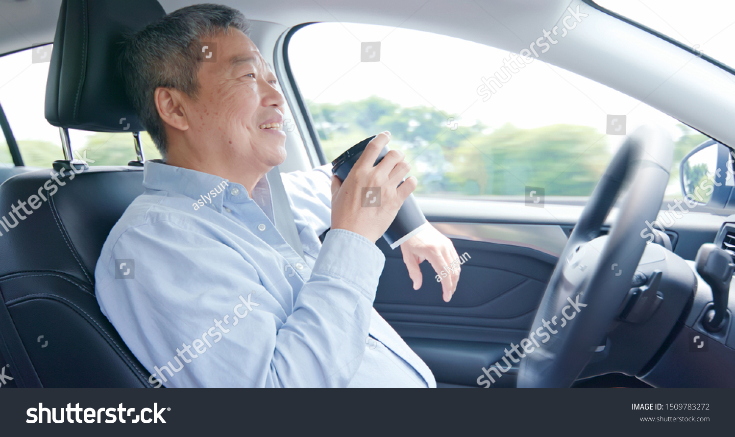 asian elderly man experience self-driving smart car and has a cup of coffee