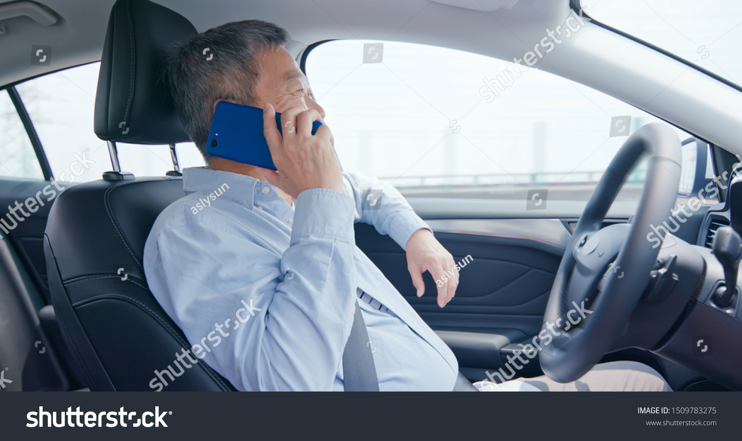 asian elderly man speak phone and drive an auto self-driving smart car in highway