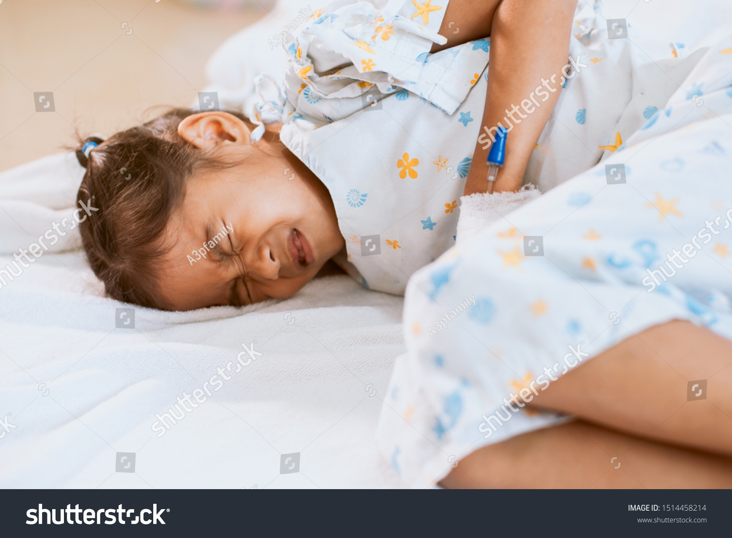Sick asian child girl who have IV solution bandaged suffering from stomachache and feeling unwell in the hospital