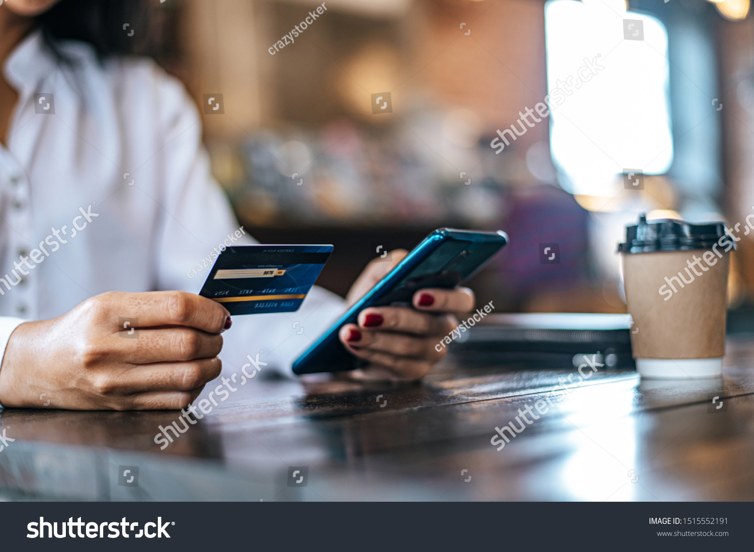 Pay for goods by credit card through a smartphone in a coffee shop.