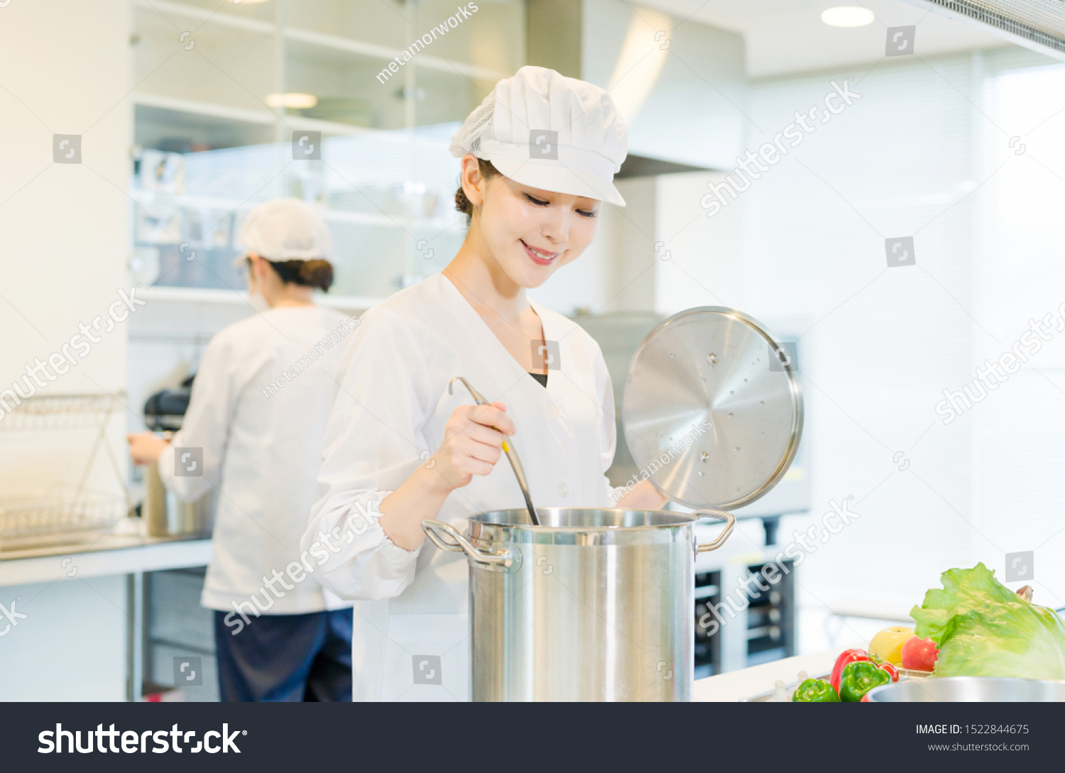 Asian female cooking staff working in kitchen.