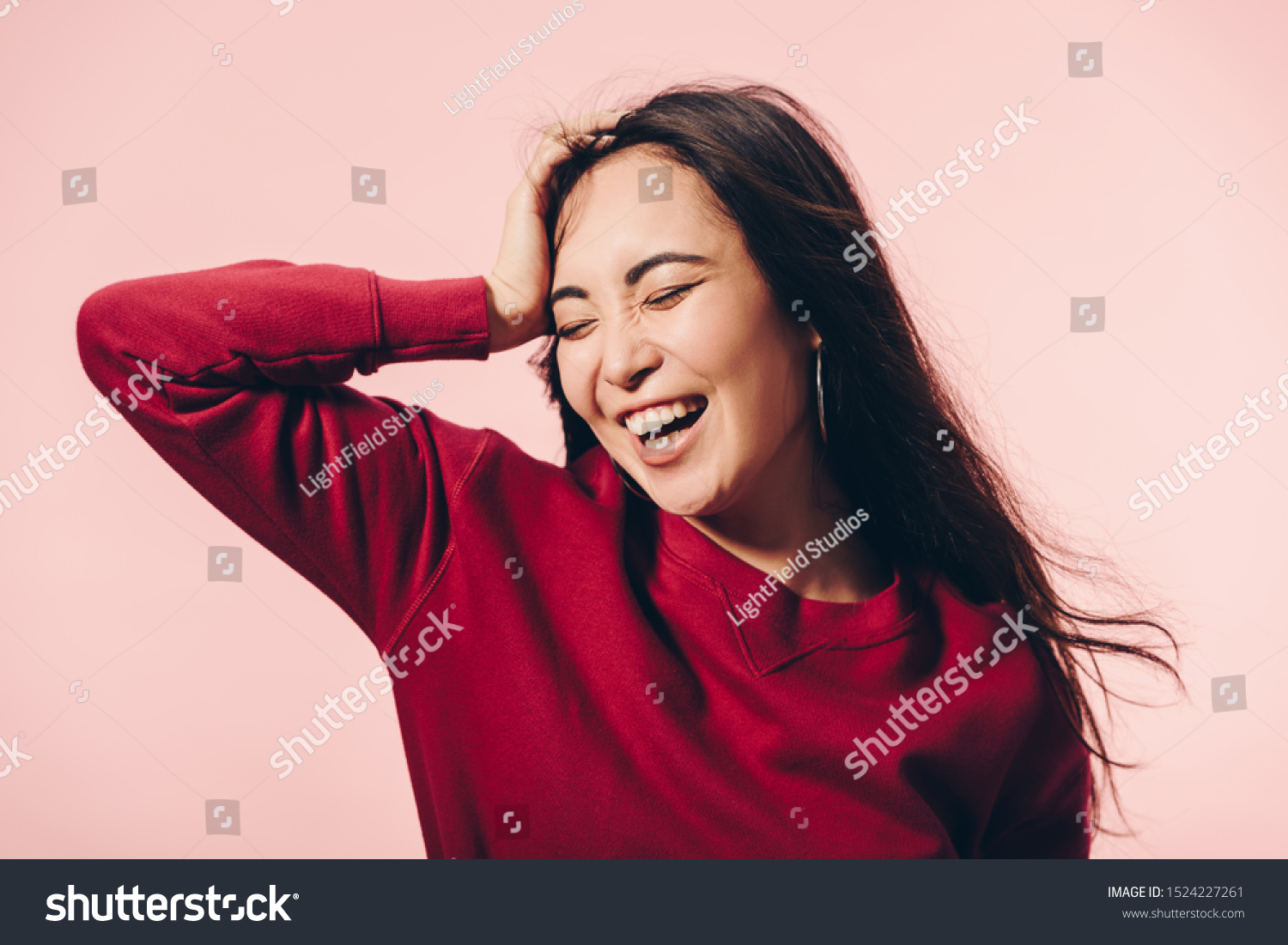 attractive asian woman in red sweater with closed eyes smiling isolated on pink 