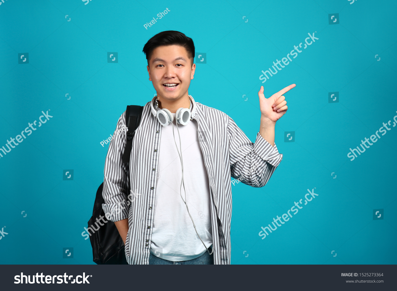 Portrait of Asian student pointing at something on color background