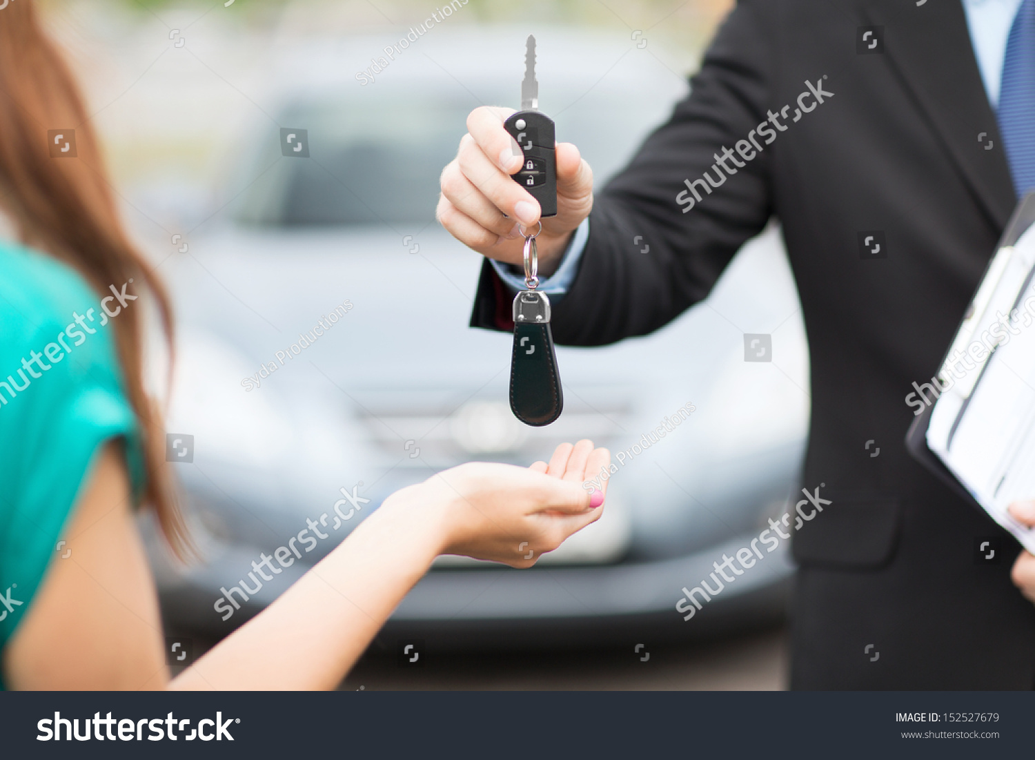 transportation and ownership concept - customer and salesman with car key outside
