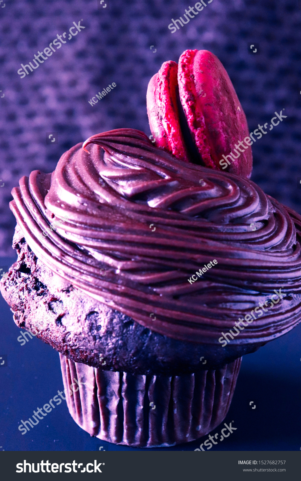 Closeup of a cupcake with a red macaron  festive neon red and blue color split hue.