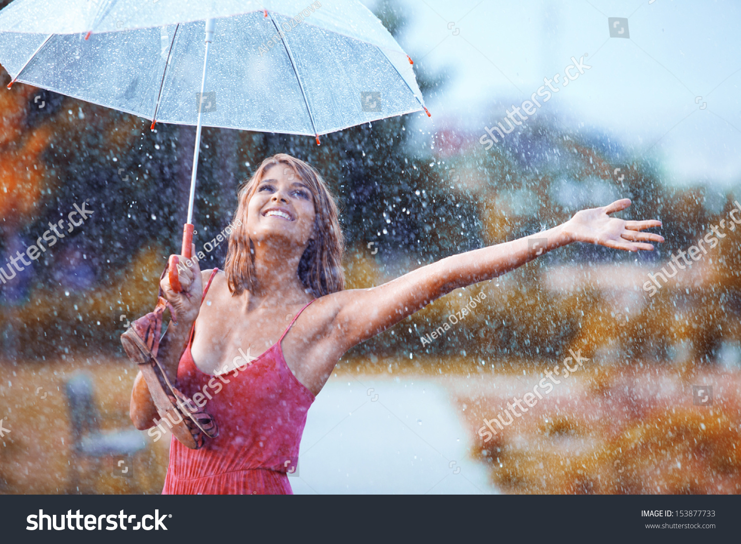 Portrait of beautiful young girl walking with umbrella under rain