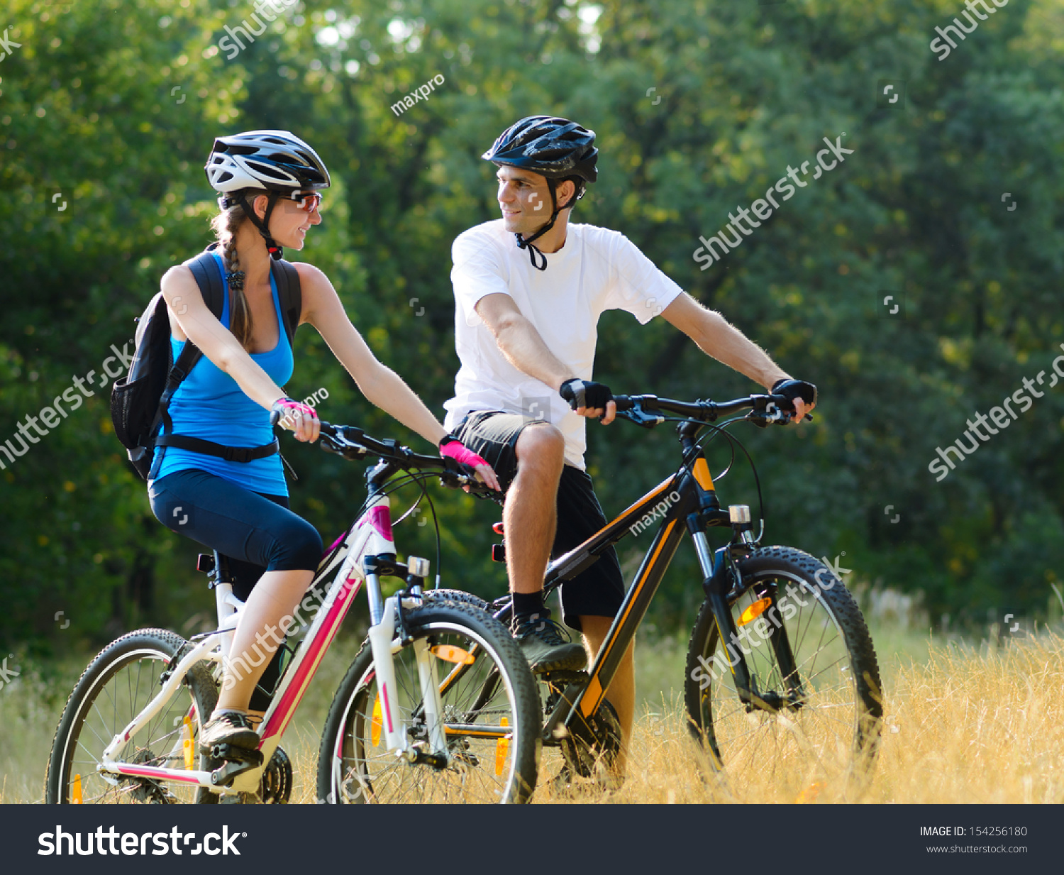 Young Happy Couple Riding Mountain Bikes Outdoor. Healthy Lifestyle Concept