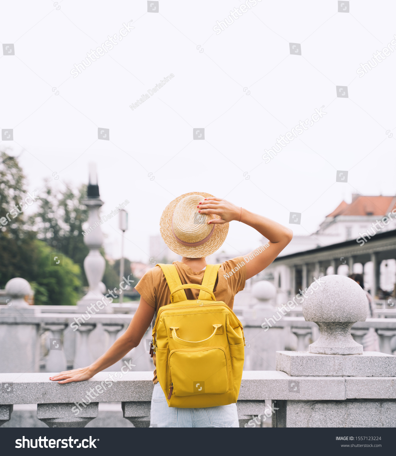Travel Slovenia Europe. Young girl with backpack on Triple Bridge in heart of Ljubljana Old Town. Back view of woman tourist on the background of city architecture. Local living in Ljubljana