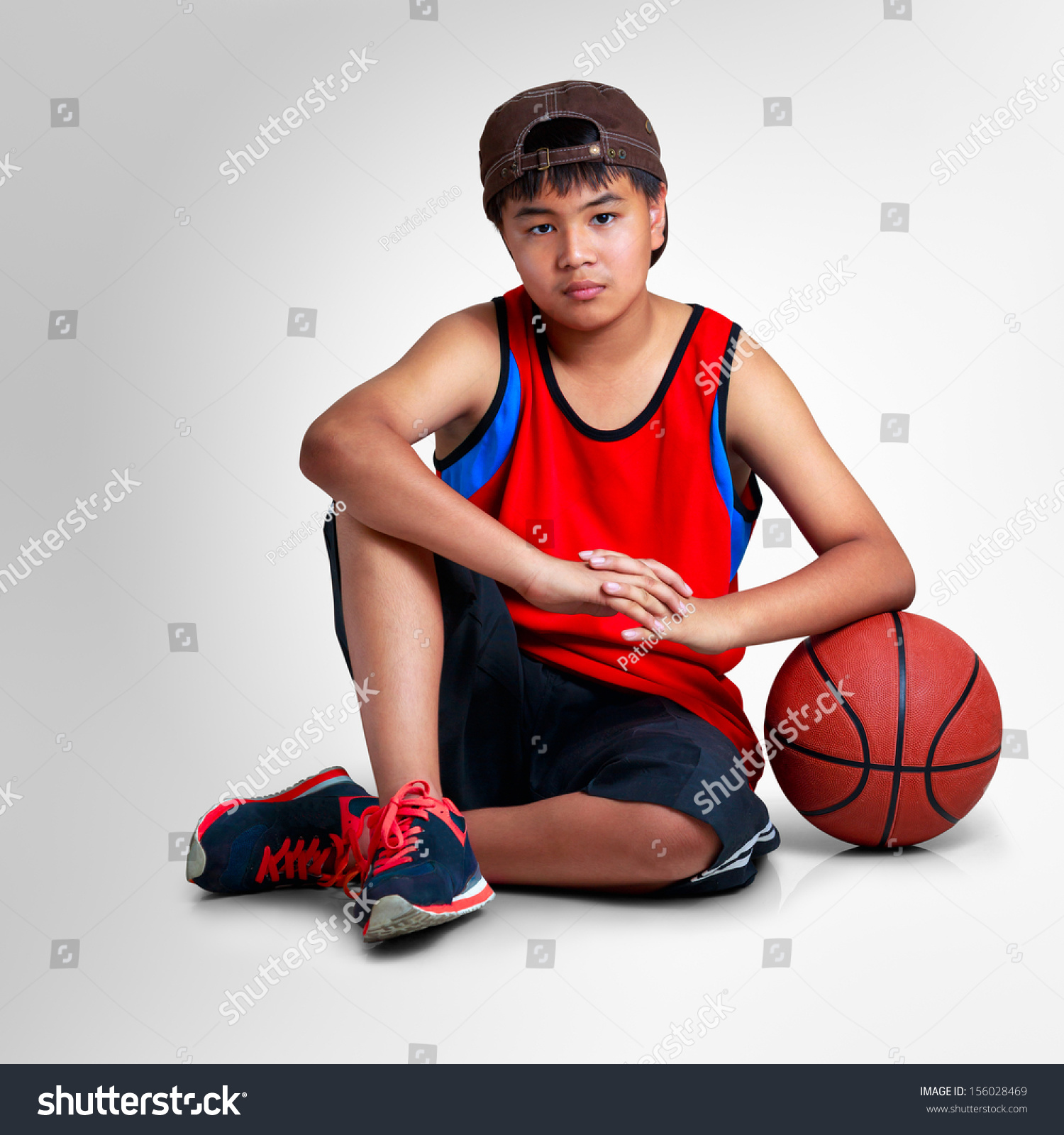 Asian boy sitting with basketball on grey background with clipping path