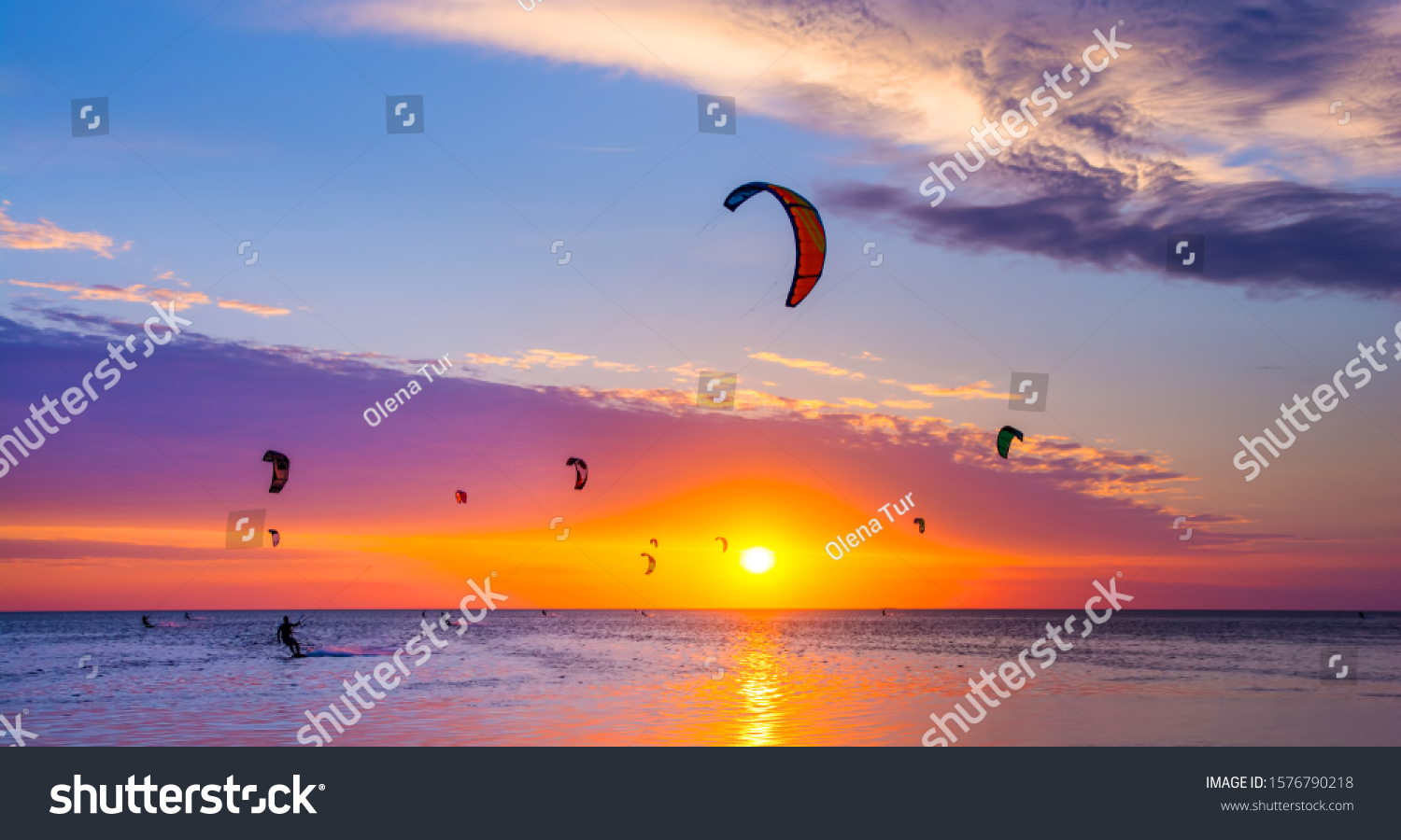 Kite-surfing against a beautiful sunset. Many silhouettes of kites in the sky. Travel concept. Artistic picture. Beauty world. Panorama