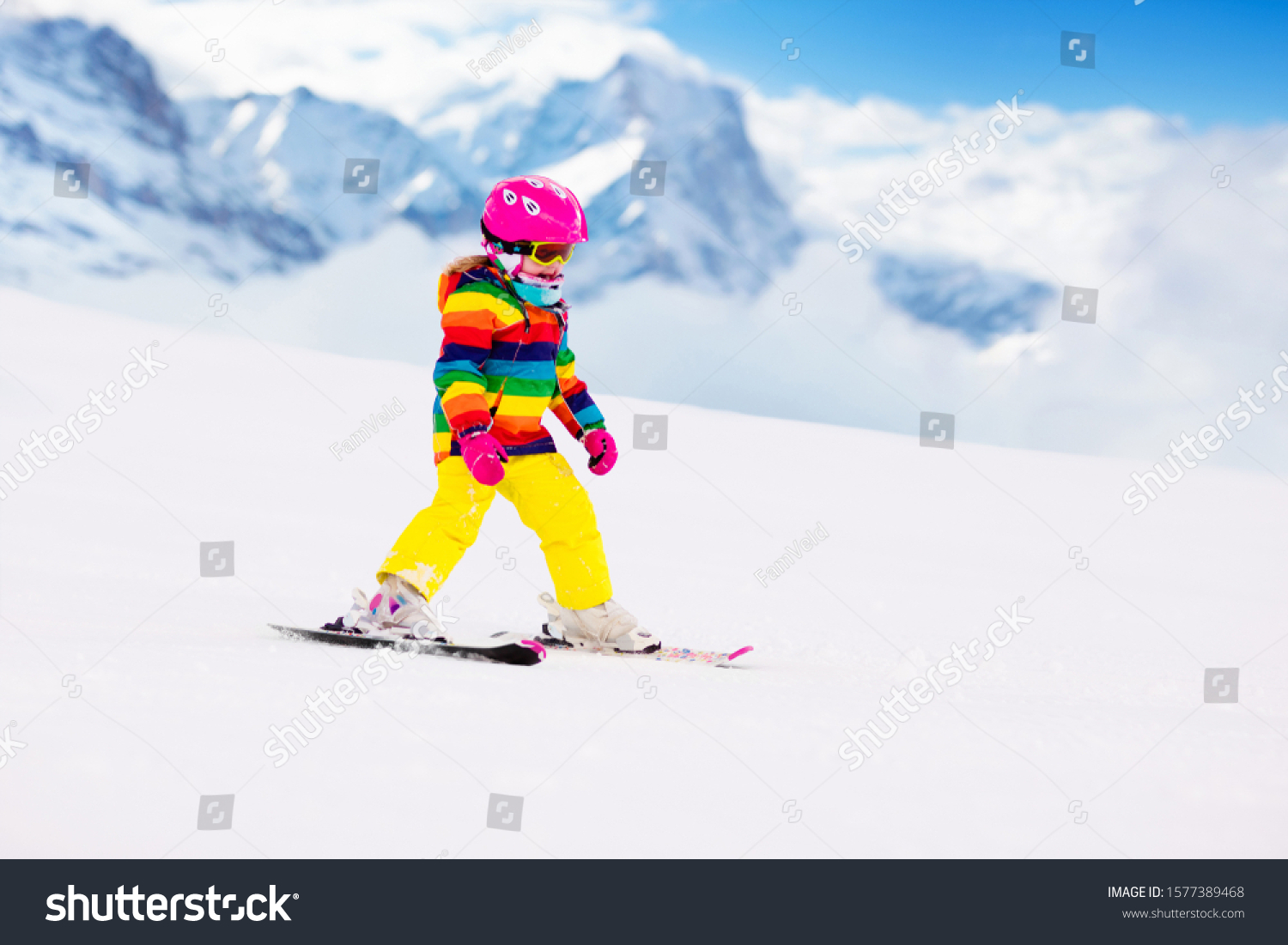 Child skiing in mountains. Active toddler kid with safety helmet goggles and poles. Ski race for young children. Winter sport for family. Kids ski lesson in alpine school. Little skier racing in snow