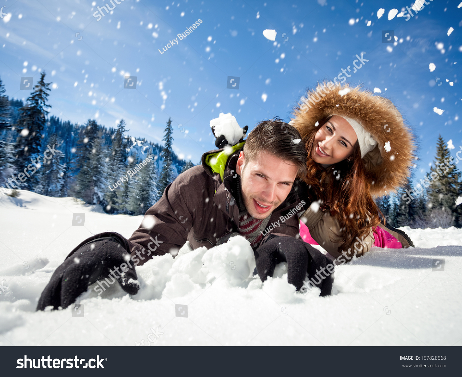 Portrait of joyful woman throwing snowball at man