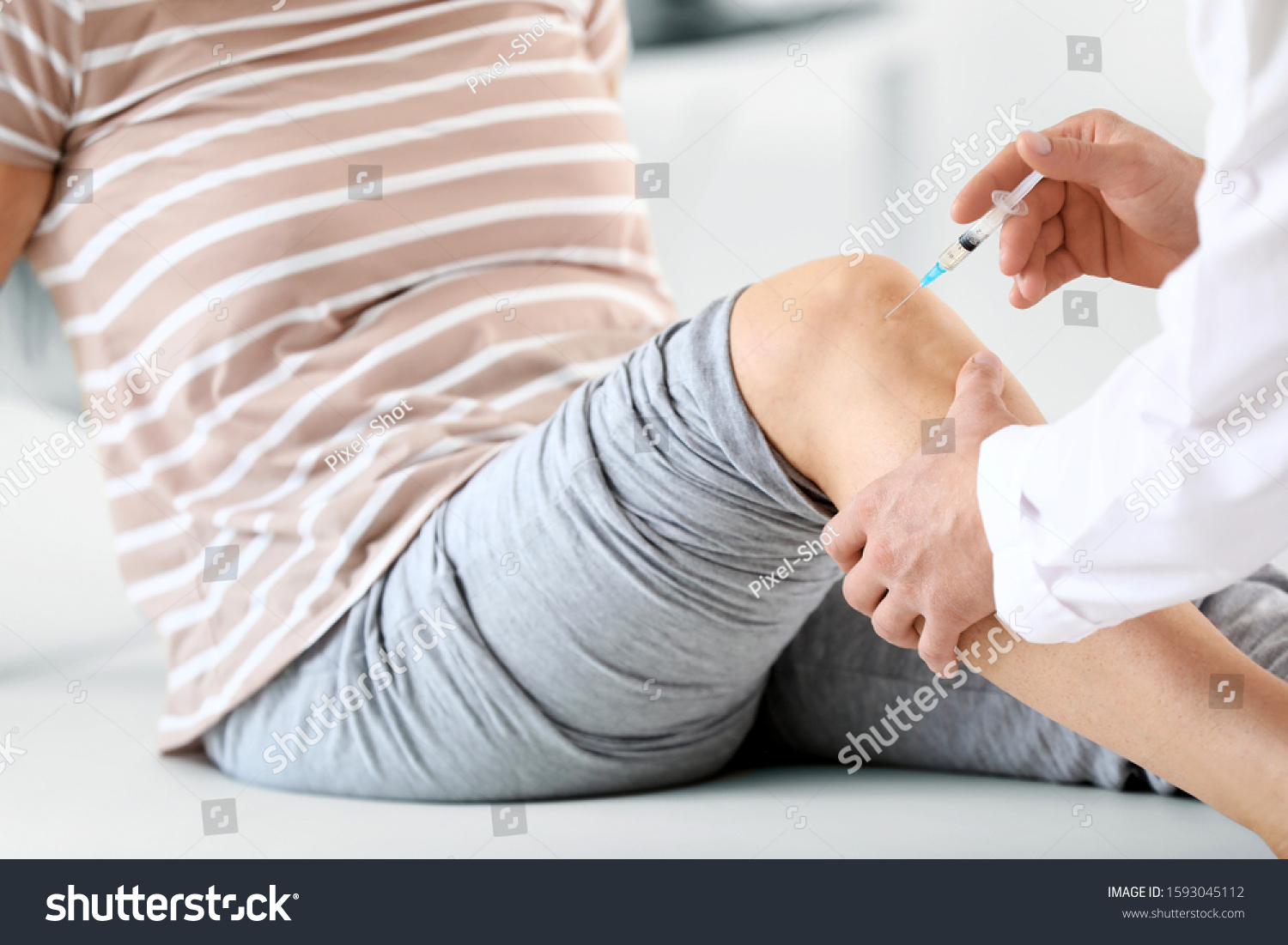 Doctor giving mature woman with joint pain injection in clinic  closeup