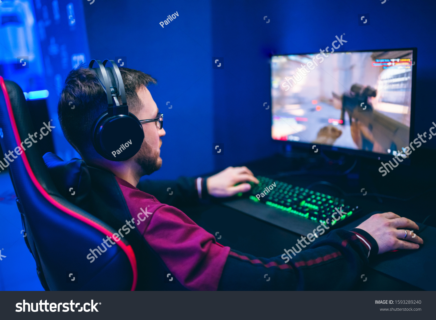 Professional gamer playing online games tournaments pc computer with headphones Blurred red and blue background.