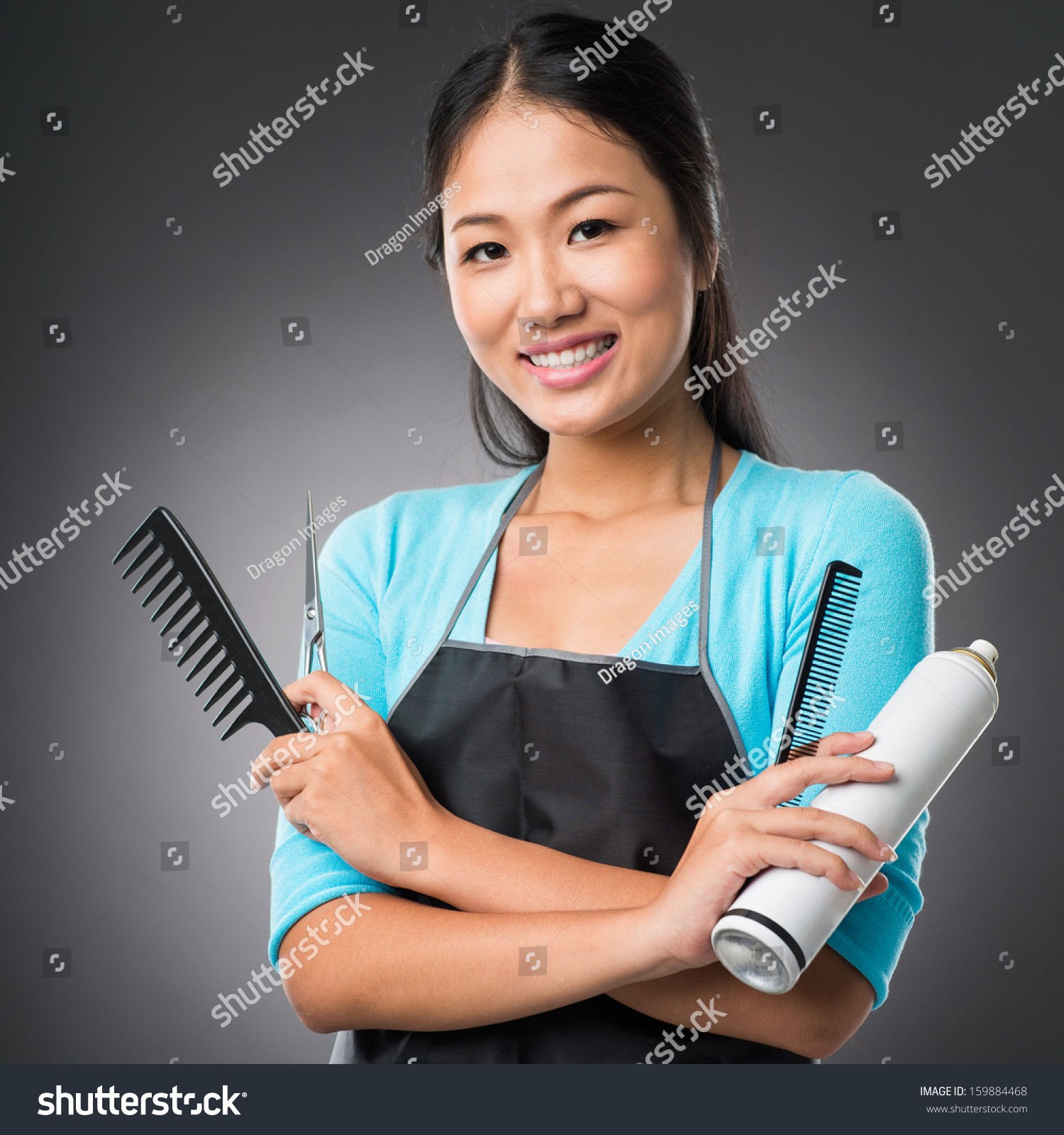 Portrait of a young female stylist with necessary equipment isolated on grey