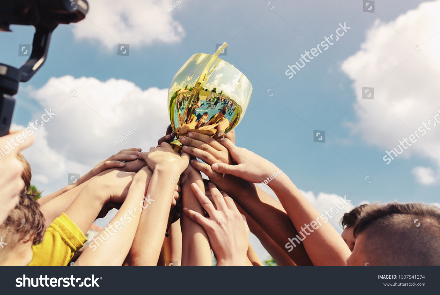Kids in sports team lift up the golden cup trophy after winning the final tournament match. Children celebrate success in sports. Winning championship in sports