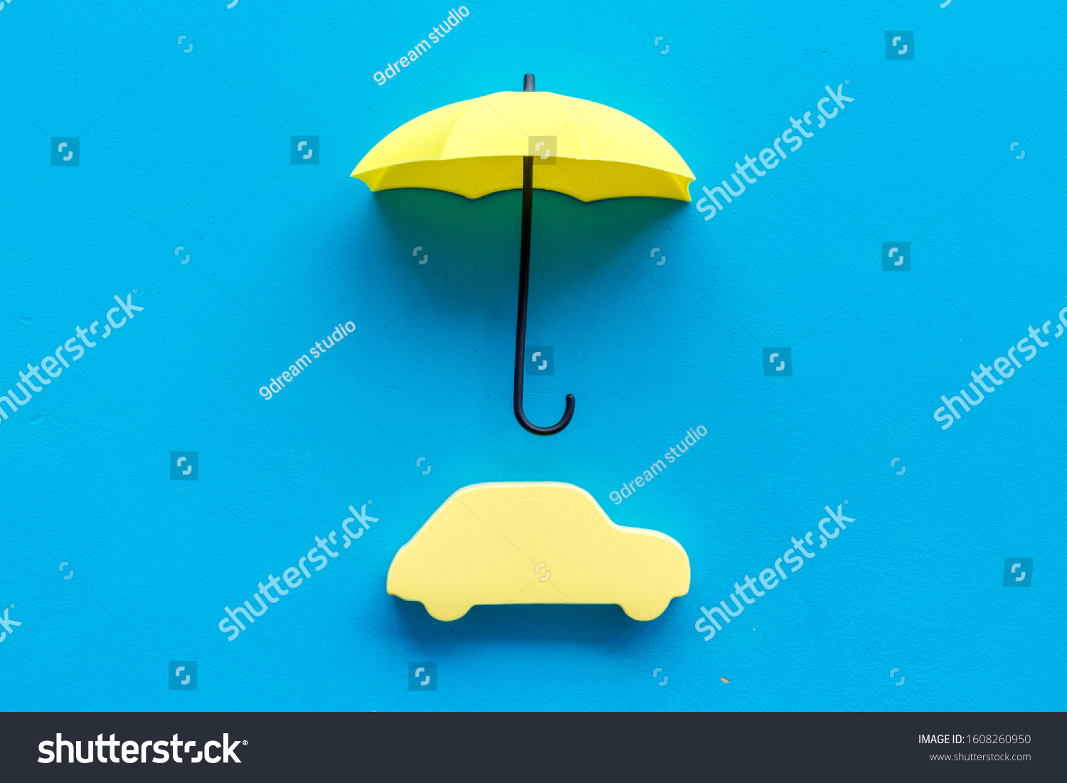 Car insurance. Automobile toy under umbrella on blue background top-down copy space