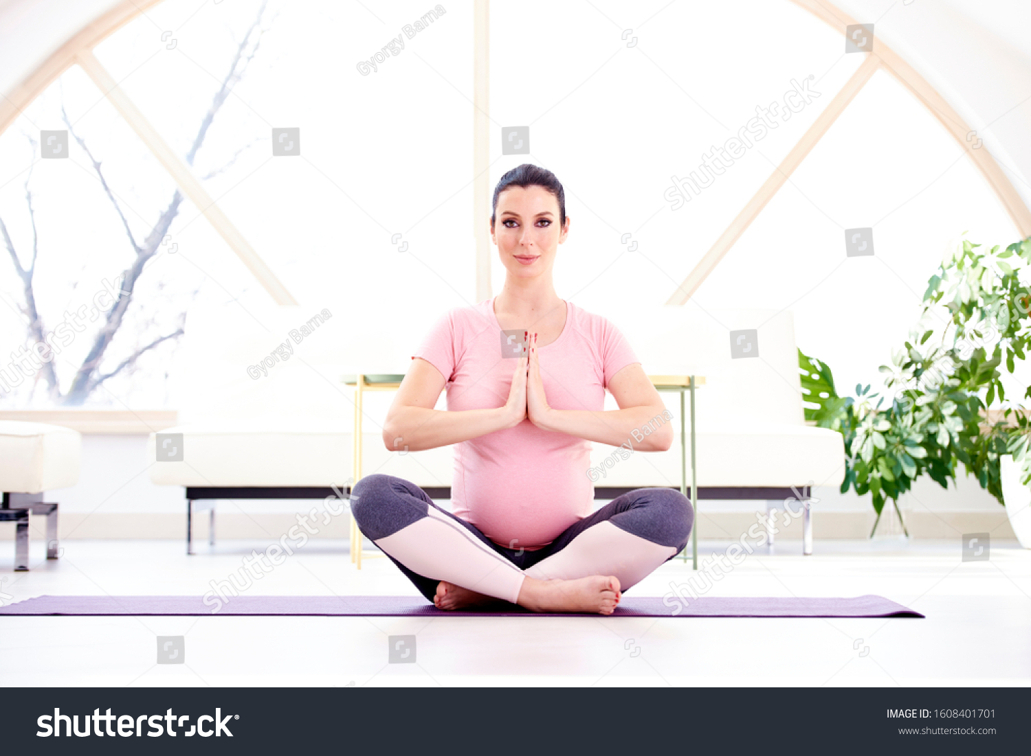 shot of beautiful pregnant woman sitting in yoga pose and medita