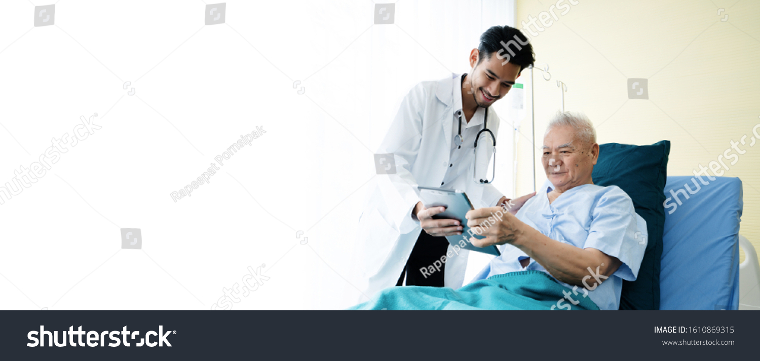 Asian man doctor uses a tablet to explain the treatment of senior male patients lying in hospital beds. Modern medical care Use technology to treat Concept of looking after elderly and retirees