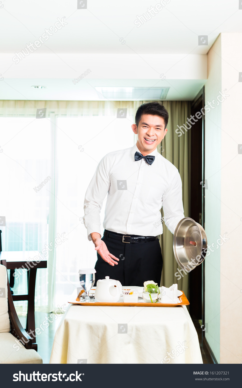 Asian Chinese room service waiter or steward serving guests food in a grand or luxury hotel room