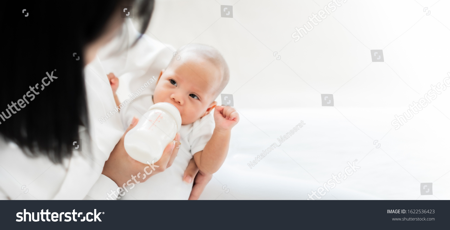 Mother feeding asian baby with bottle of milk  banner copy space