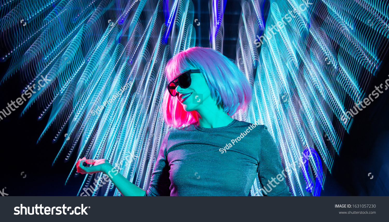 nightlife fashion and people concept - happy young woman wearing pink wig and black sunglasses dancing at nightclub over neon ultraviolet lights background