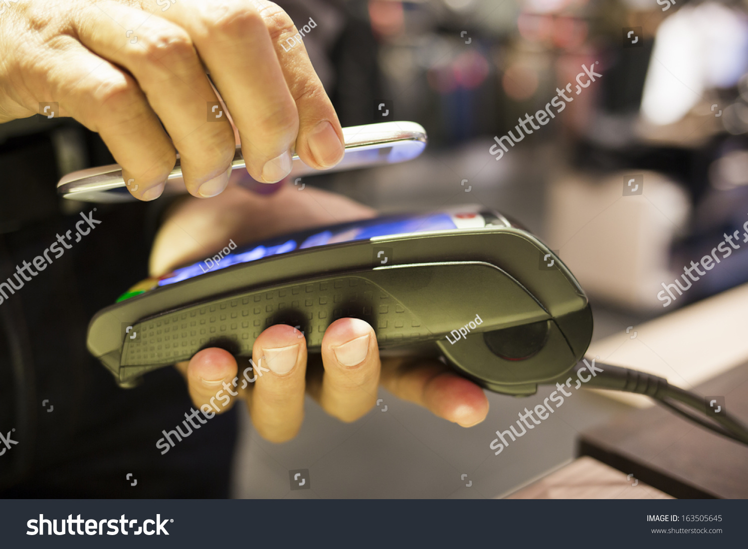Man paying with NFC technology on Cell Phone  in clothing store