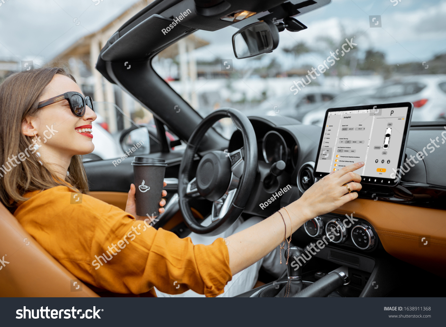 Cheerful woman controlling car with a digital dashboard switching autopilot mode while driving a cabriolet. Smart car concept