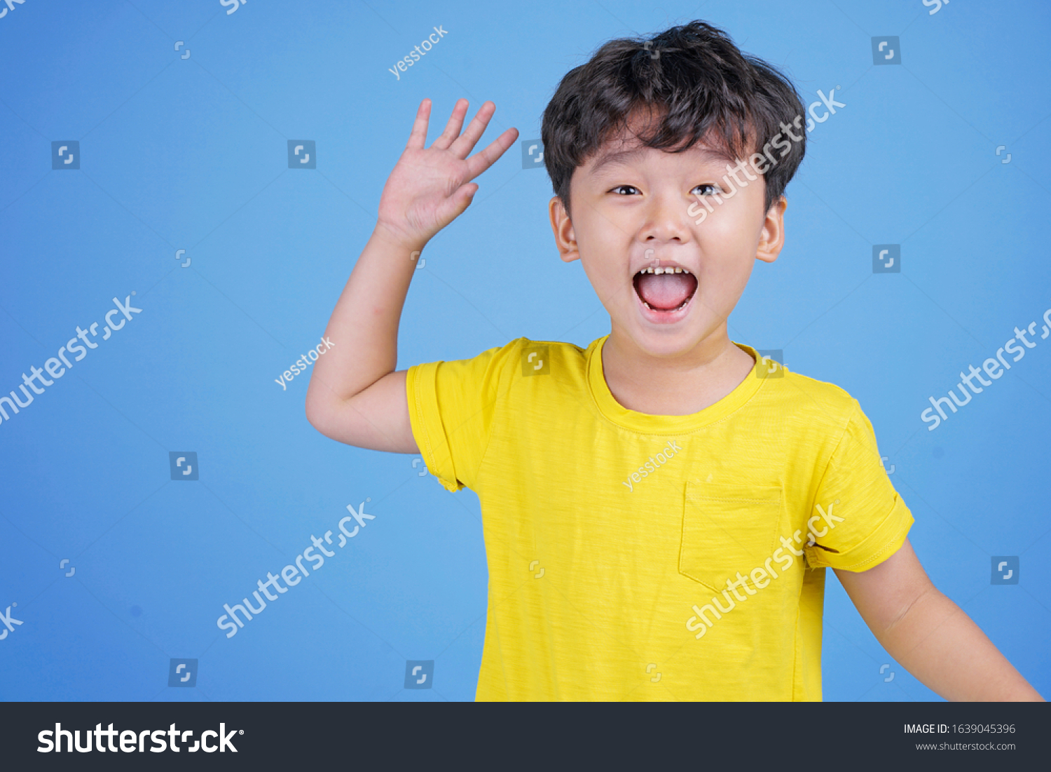 Close up portrait of cute boy pointing with finger gesture  isolated on blue background