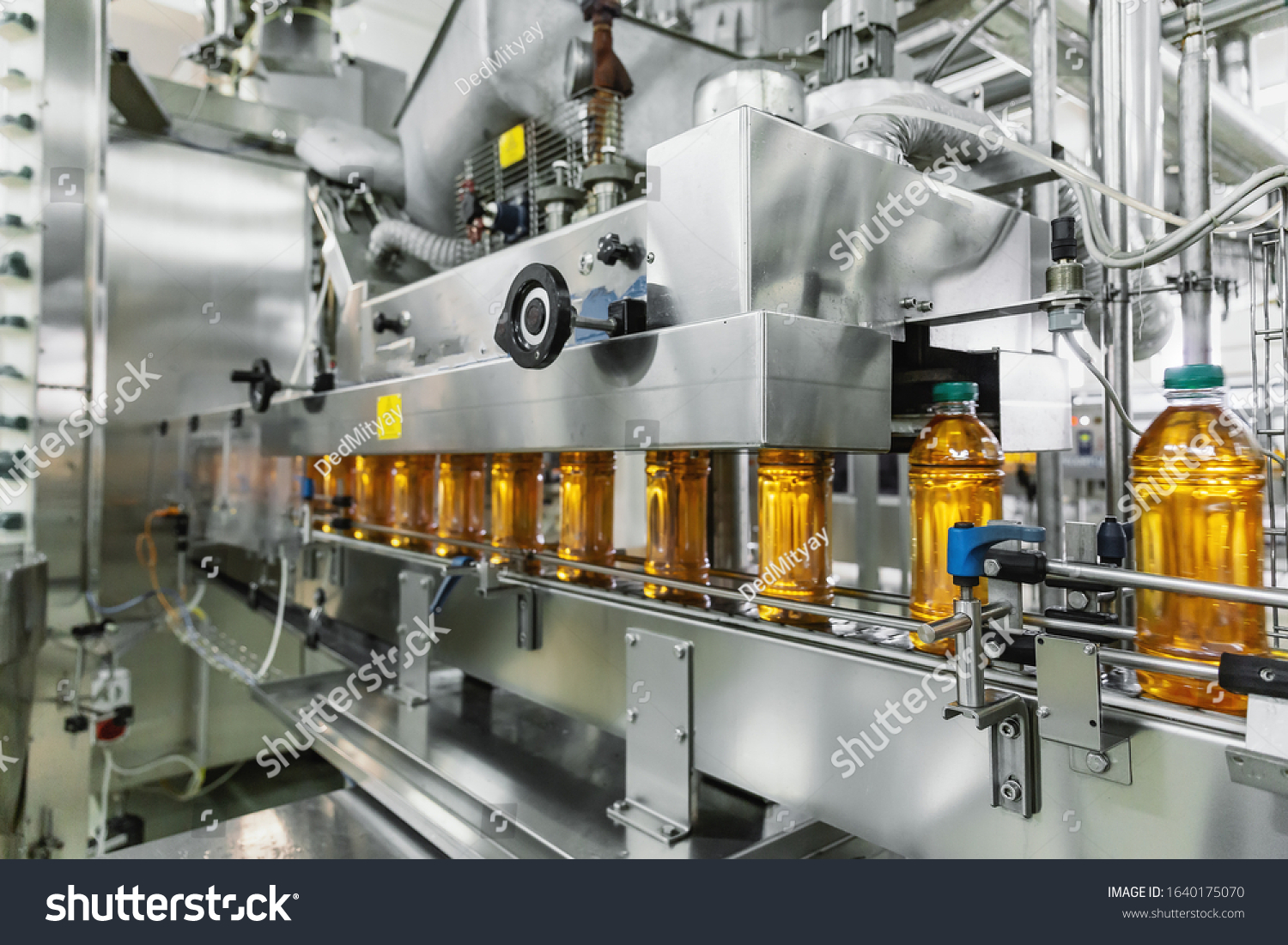 Industrial interior of natural juice plant production. Conveyor belt filled bottles on beverage factory industry production line.