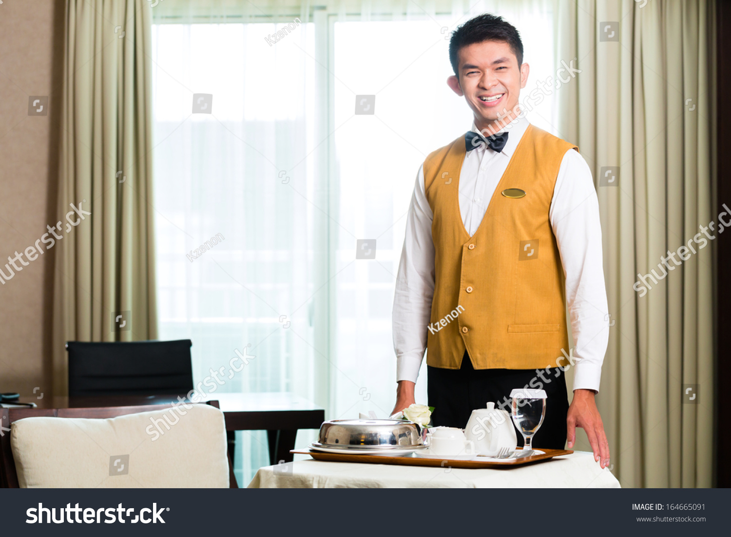 Asian Chinese room service waiter or steward serving guests food in a grand or luxury hotel room