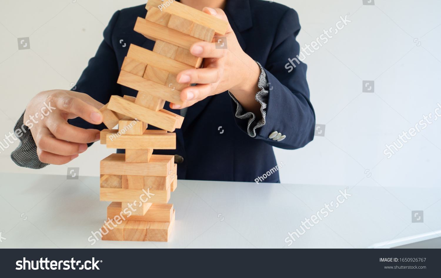 Business woman’s hand is protecting falling blocks while the other hand making risk.