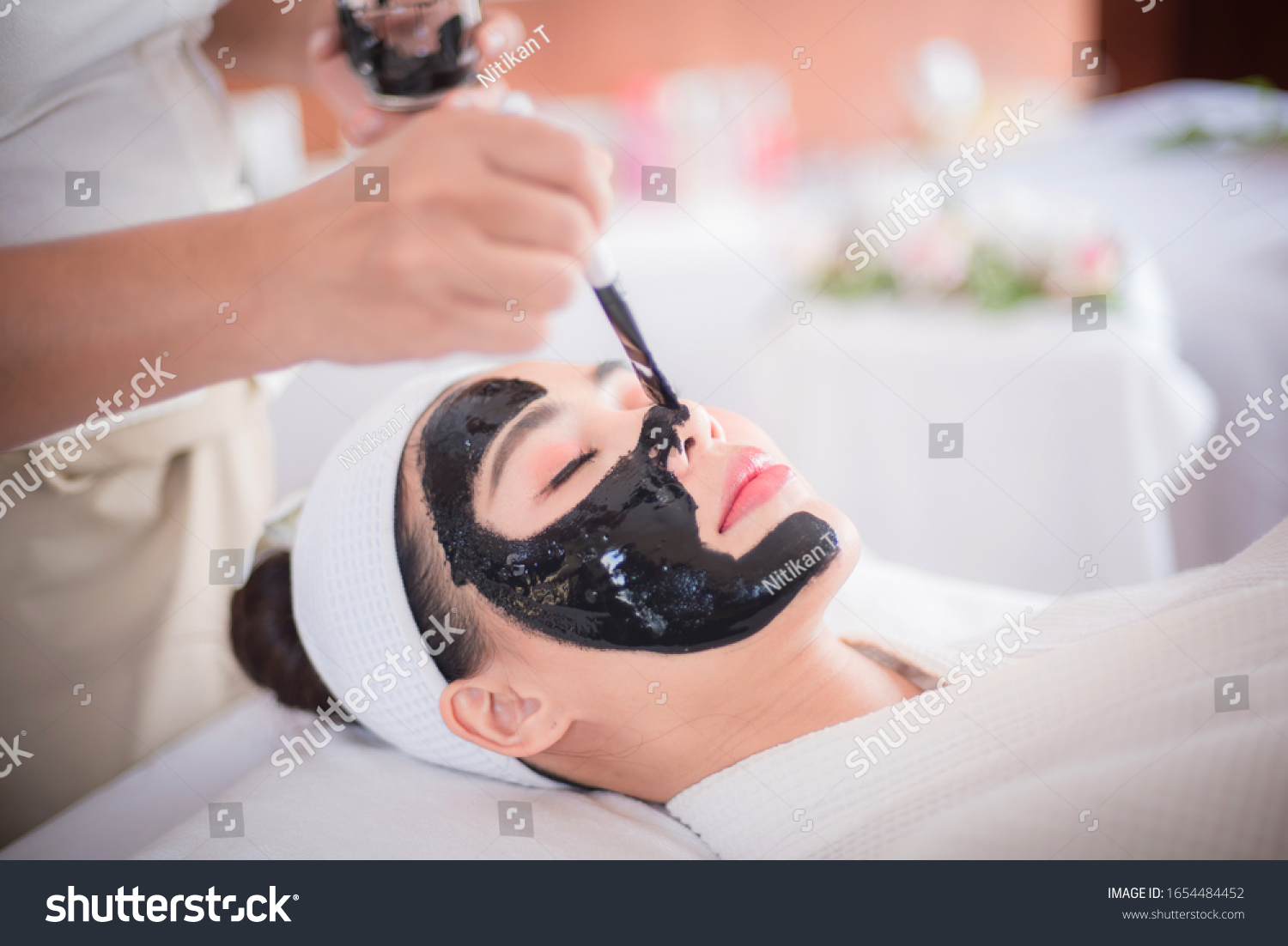 Spa and beauty room  black face mask of mud and algae  an Asian woman lying on the bed  waiting for a mask expert on a beautiful face.
