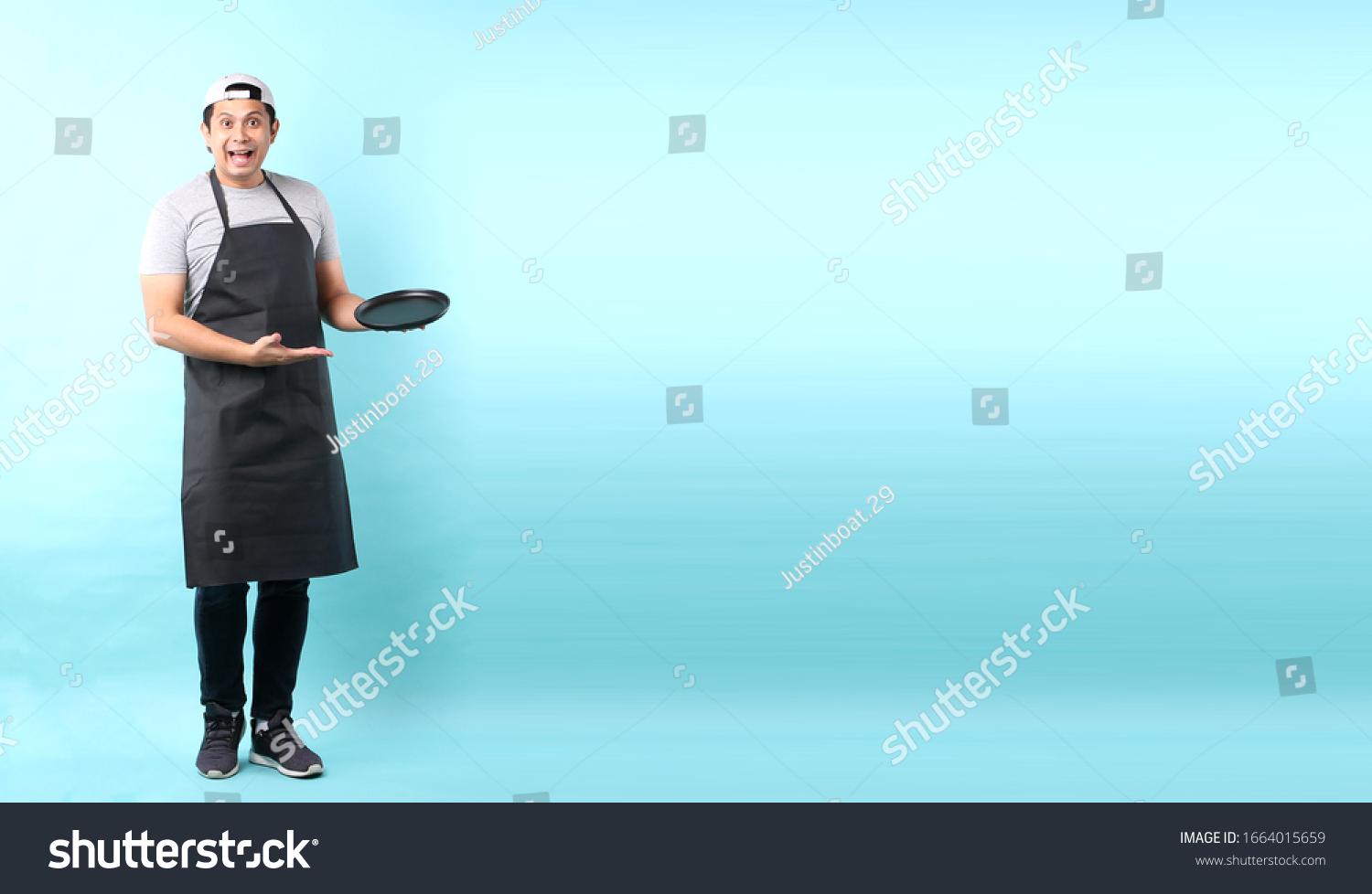 Dining concept. Asian man waiter holding an empty plate.isolated on blue background in studio With copy space.
