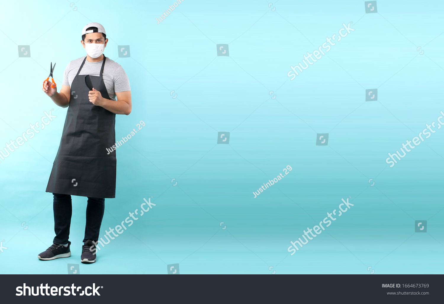 Full body Portrait of cheerful positive barber with  having scissors in hand and Comb isolated on blue background in studio With copy space.