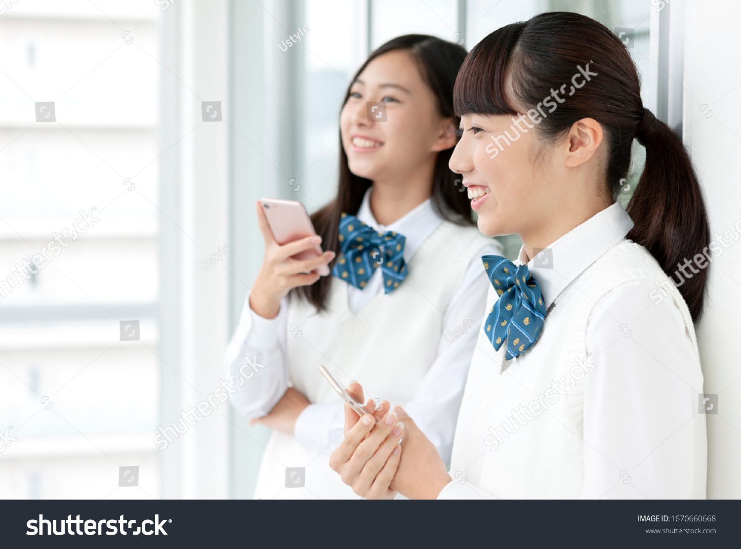 Female student in uniform with smartphone
