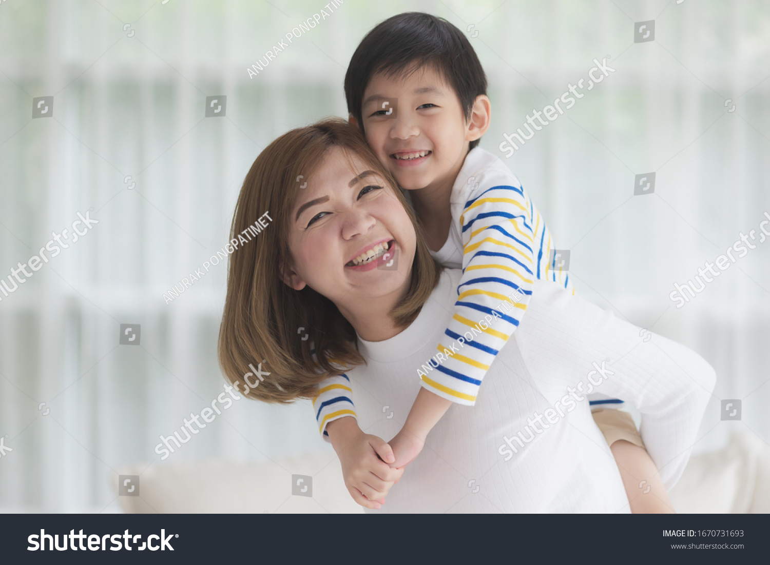 Asian child on a piggy back ride with his mother at home