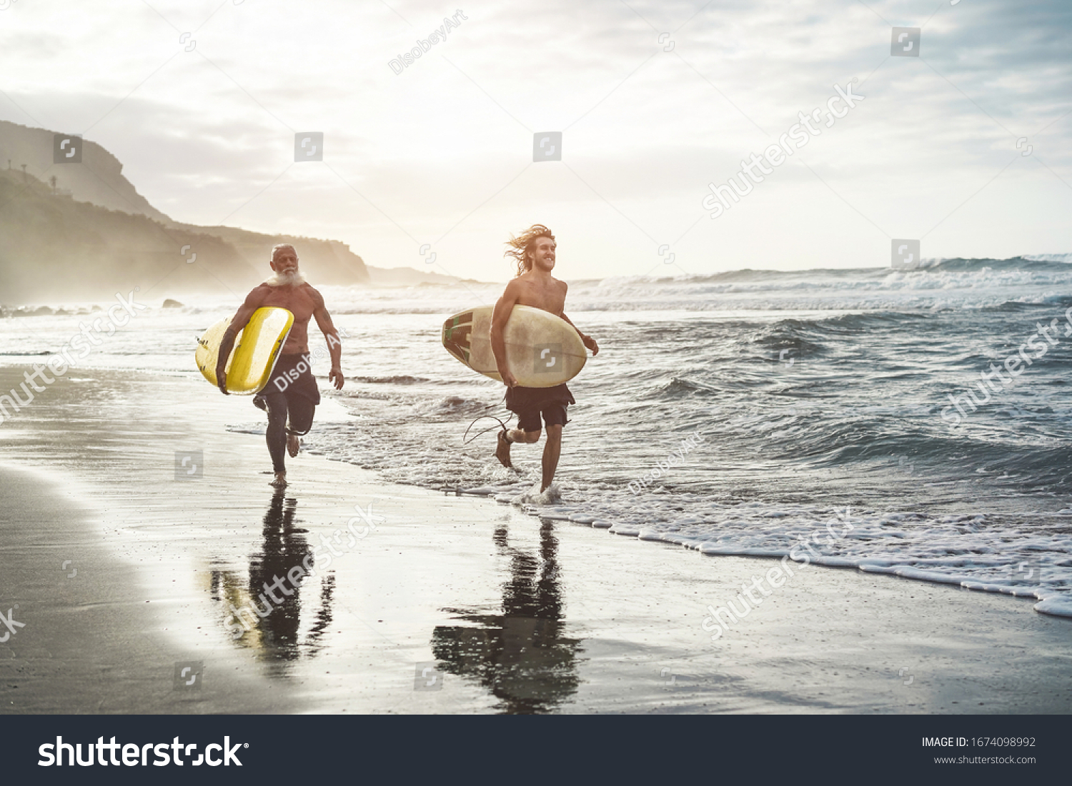 Multigeneration friends going to surf on tropical beach - Family people having fun doing extreme sport - Joyful elderly and healthy lifestyle concept - Main focus on young guy face