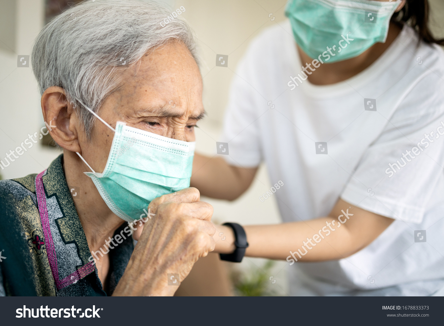 Sick elderly woman with coughing and fever risk symptoms of flu pandemic of Covid-19 asian daughter wearing protective mask to senior mother prevent outbreak or spread of Coronavirus to other people