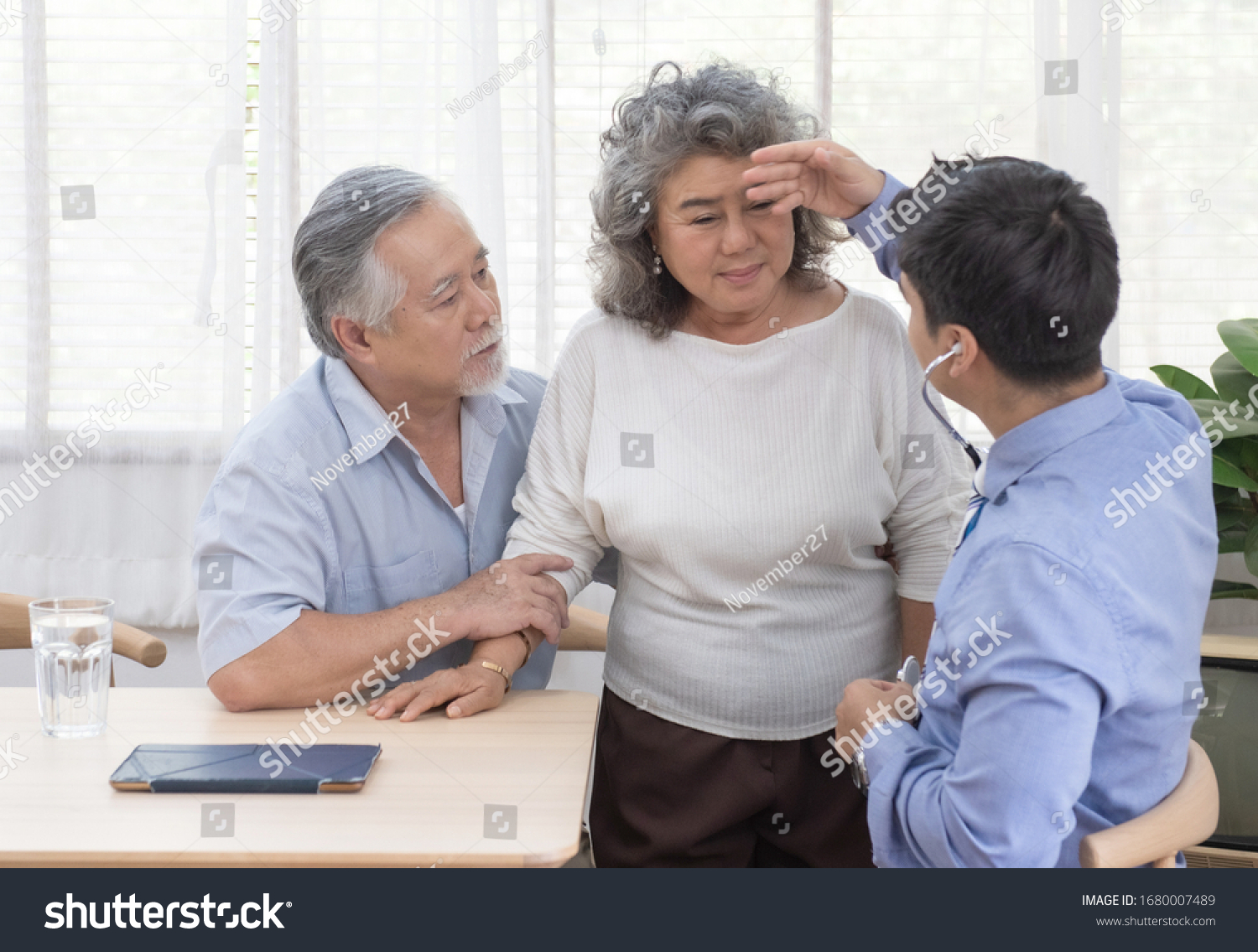 Caucasian doctor use stethoscope and talk with old asian female patient about disease symptom elderly health check up at home.