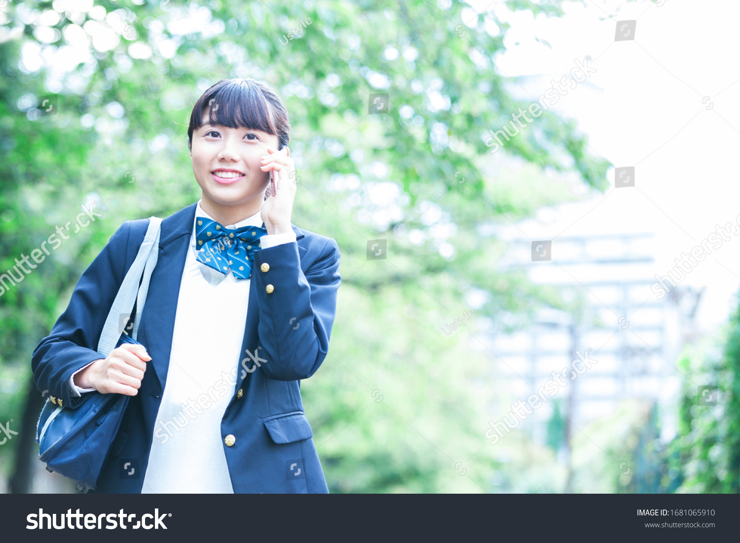 A female student in a uniform making a phone call