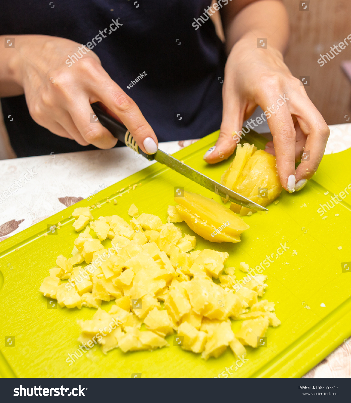 girlcutsboiledpotatoeswithaknifeonaplasticboard